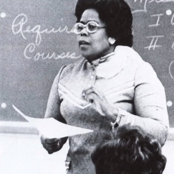 Graphic labeled 'Omaha City Council' featuring a black-and-white photo of a female teacher lecturing at a chalkboard, holding papers as a student listens nearby